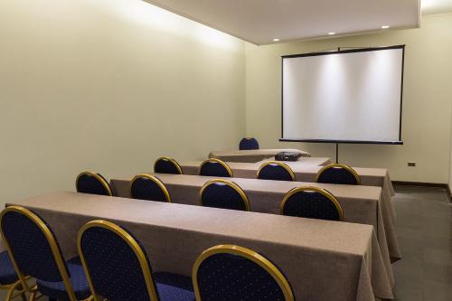 a conference room with tables and chairs and a screen at Hotel Club La Serena in La Serena