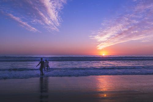 a couple of people walking on the beach with a surfboard at Hotel Club La Serena in La Serena