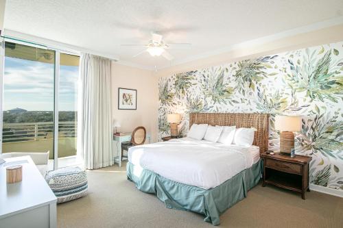 a bedroom with a large bed with a tropical wallpaper at Ocean Club 703 in Biloxi