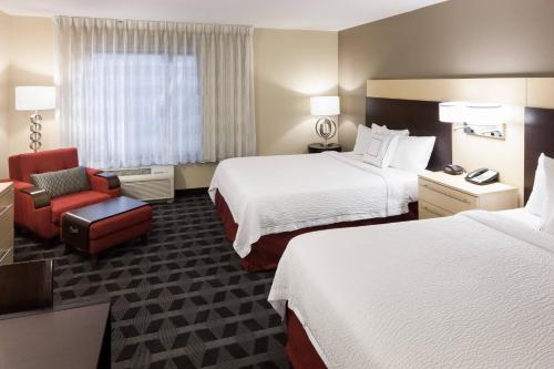 a hotel room with two beds and a red chair at TownePlace Suites by Marriott Little Rock West in Little Rock