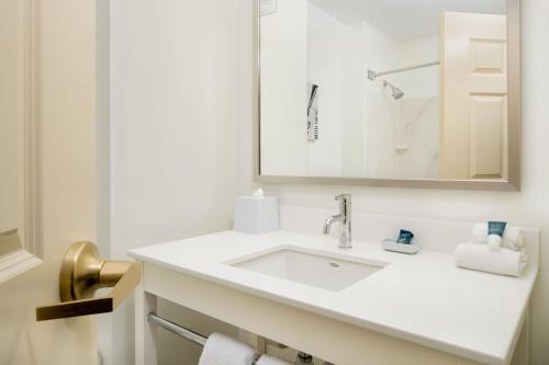 Baño blanco con lavabo y espejo en Four Points by Sheraton Louisville Airport en Louisville