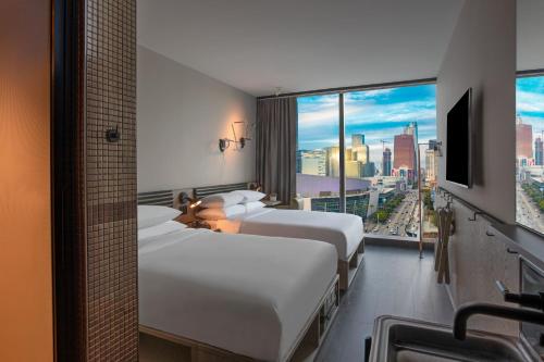 a hotel room with two beds and a large window at Moxy Downtown Los Angeles in Los Angeles
