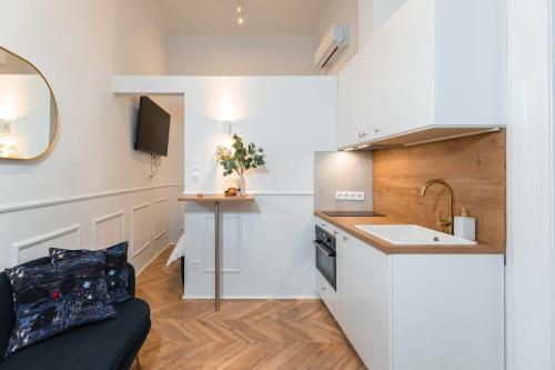 uma cozinha com armários brancos, um lavatório e um sofá em Charming studio - in the downtown em Budapeste