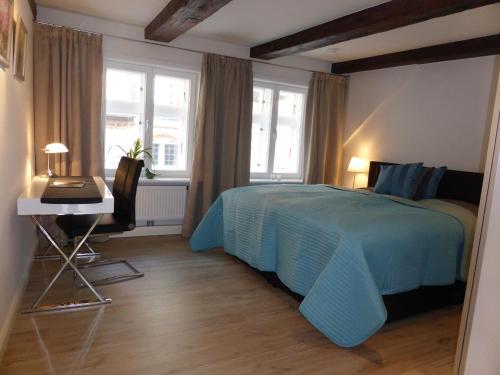 a bedroom with a blue bed and a desk and window at Meeresleuchten in Lüneburg