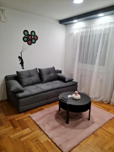 a living room with a black couch and a table at Apartman Vinyl - self chek-in in Osijek