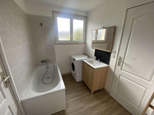 La salle de bains est pourvue d'une baignoire, d'un lavabo et de toilettes. dans l'établissement Maison de vacances normande entre Cabourg et Caen, à Troarn
