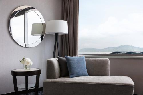 a living room with a chair and a mirror at Hong Kong SkyCity Marriott Hotel in Hong Kong