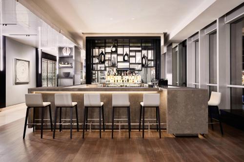 a bar with white bar stools in a room at AC Hotel by Marriott Santiago Costanera Center in Santiago
