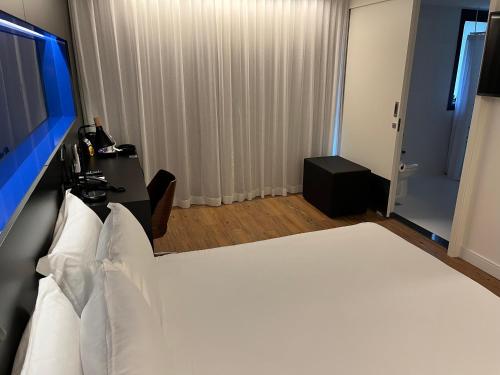 a bedroom with a white bed and a bathroom at Park Plaza Moinhos Porto Alegre in Porto Alegre
