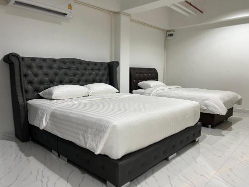two beds in a room with white sheets and pillows at Mall Suites Hotel in Bangkok