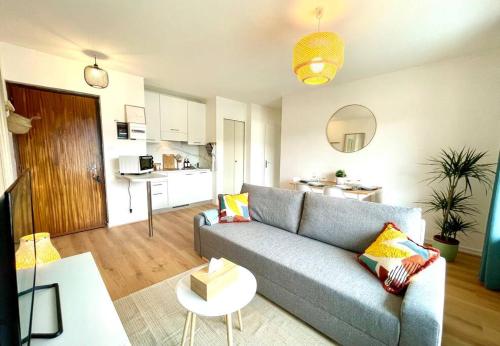 un salon avec un canapé bleu et une cuisine dans l'établissement Appartement - Lit Queen Size - Proximité Genève, à Saint-Julien-en-Genevois