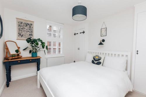 Habitación blanca con cama blanca y escritorio. en The Poppies, en Henley on Thames