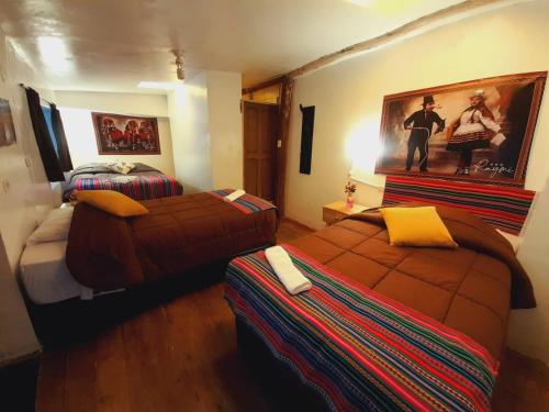 a bedroom with two beds and a painting on the wall at Hostal Raymi in Ollantaytambo
