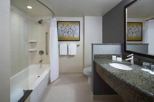 ein Badezimmer mit einem Waschbecken, einer Badewanne und einem WC in der Unterkunft Courtyard by Marriott Montreal Airport in Dorval