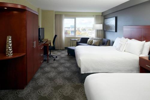 a hotel room with two beds and a couch at Courtyard by Marriott Montreal Airport in Dorval