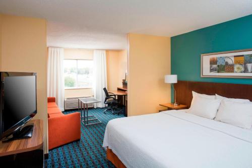 a hotel room with a bed and a flat screen tv at Fairfield Inn & Suites Greeley in Greeley