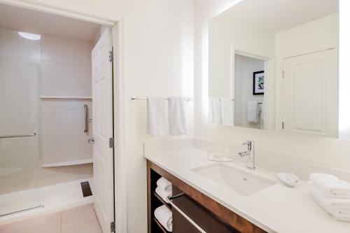 Baño blanco con lavabo y espejo en Residence Inn by Marriott Jacksonville Butler Boulevard en Jacksonville