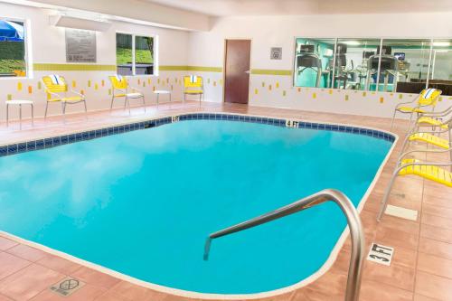 a large pool in a hotel room with chairs and tables at Fairfield Inn Tuscaloosa in Tuscaloosa