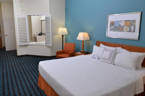 a hotel room with a bed and a chair and a mirror at Fairfield Inn & Suites Effingham in Effingham