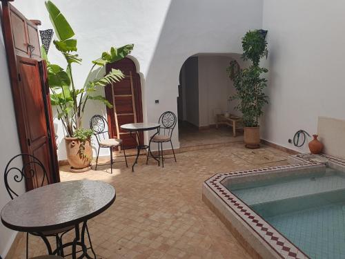 Habitación con piscina, mesas y sillas en Riad Le Manzil Beldi en Marrakech