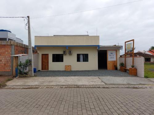 a small white building sitting on top of a street at Pousada Pontal da Armação in Penha