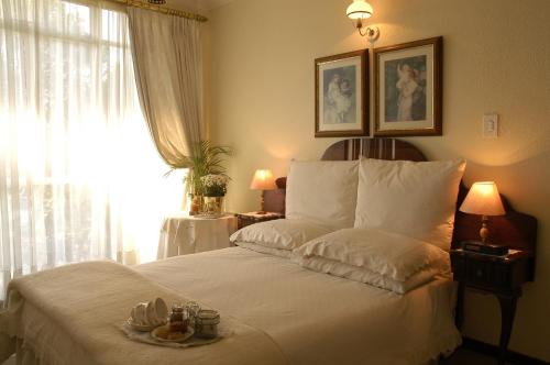 1 dormitorio con 1 cama blanca grande y ventana en Elonda B&B, en Pretoria