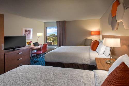 Habitación de hotel con 2 camas, escritorio y TV. en Fairfield Inn Las Vegas Convention Center, en Las Vegas