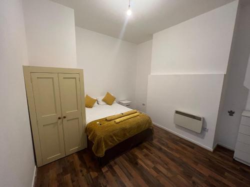 a small white bedroom with a bed with yellow sheets at ☆ Property Buzzer Serviced Apartments ☆ 1 Bed Flat Birmingham City Centre - China Town ☆ Very close to Bull Ring, Grand Central + Mailbox ☆ in Birmingham