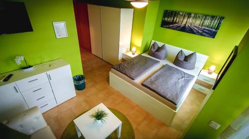 um pequeno quarto com uma cama com paredes verdes em Pension Village em Naumburg