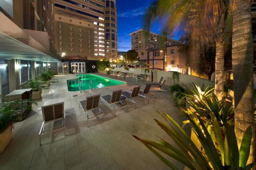 um pátio com uma piscina, mesas e cadeiras em Courtyard by Marriott San Juan Miramar em San Juan