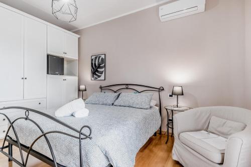 a white bedroom with a bed and a chair at B&B A casa di Giulia in Guidonia