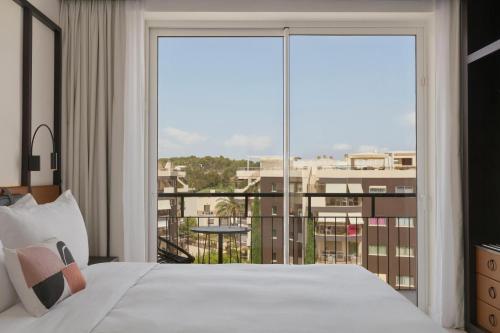 a bedroom with a bed and a large window at Hotel Riomar, Ibiza, a Tribute Portfolio Hotel in Santa Eularia des Riu