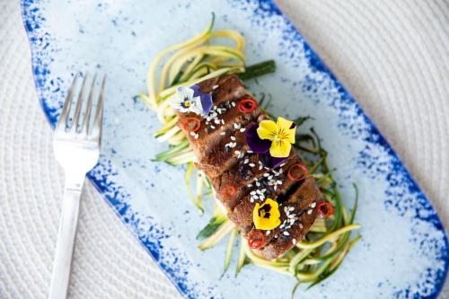 a plate of food with a piece of fish and vegetables at Hotel Riomar, Ibiza, a Tribute Portfolio Hotel in Santa Eularia des Riu