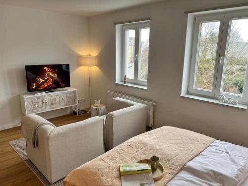 Schlafzimmer mit einem Bett, einem TV und Fenstern in der Unterkunft Smultron Apartment Altstadt Wismar in Wismar
