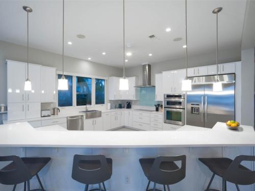 uma grande cozinha com armários brancos e cadeiras pretas em Luxury Cayman Villas em Driftwood Village