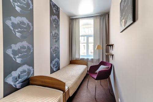 sypialnia z łóżkiem, krzesłem i oknem w obiekcie All Dreams Rooms w Petersburgu