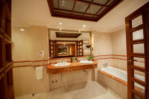 a bathroom with two sinks and a tub and a mirror at Granados Park Hotel in Asuncion