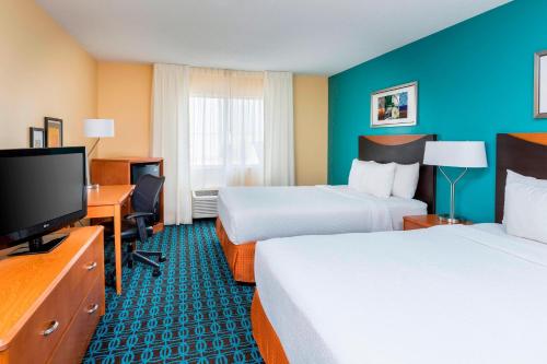 a hotel room with two beds and a flat screen tv at Fairfield Inn & Suites Lincoln in Lincoln