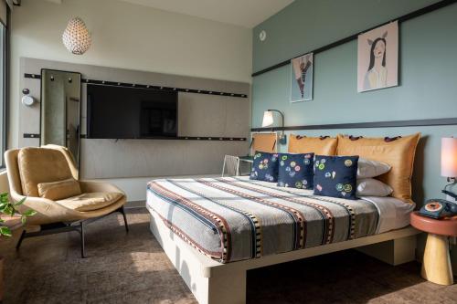 a bedroom with a bed and a chair and a television at Moxy Portland Downtown in Portland