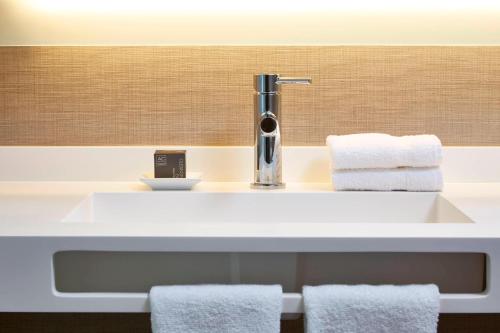 a bathroom with a sink with towels on it at AC Hotel by Marriott Atlanta Buckhead at Phipps Plaza in Atlanta