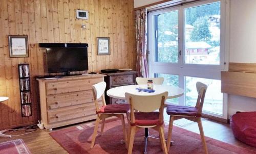 ein Wohnzimmer mit einem Tisch, Stühlen und einem TV in der Unterkunft Ferienwohnung in Anzère, an der Skipiste in Anzère