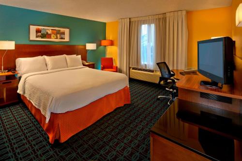 a hotel room with a bed and a flat screen tv at Fairfield Inn & Suites Boca Raton in Boca Raton