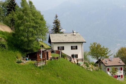 une maison blanche au sommet d'une colline verdoyante dans l'établissement Alpe Monte Massella, à Poschiavo