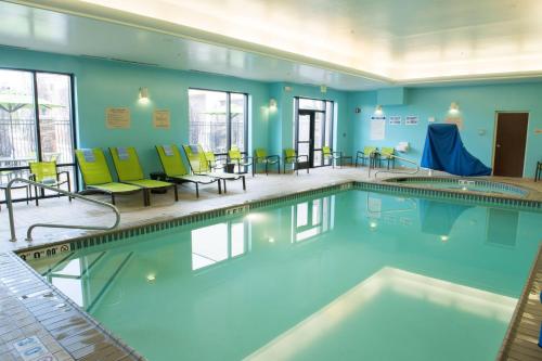 a swimming pool with chairs and tables in a building at SpringHill Suites by Marriott Logan in Logan