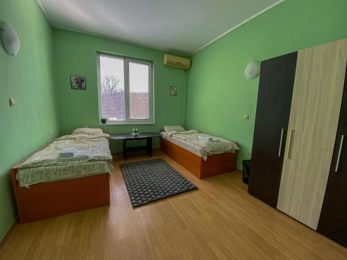een groene kamer met 2 bedden en een raam bij Пансион - Димитър Хадживасилев in Svishtov