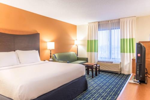 um quarto de hotel com uma cama grande e uma cadeira em Fairfield Inn & Suites by Marriott Muskegon Norton Shores em Norton Shores