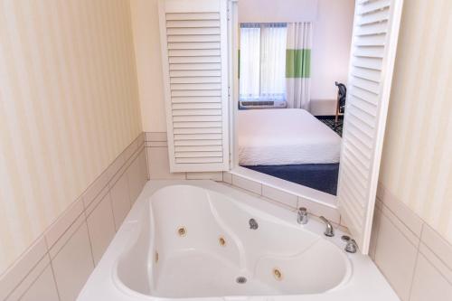 a white bath tub in a room with a bed at Fairfield Inn & Suites by Marriott Muskegon Norton Shores in Norton Shores