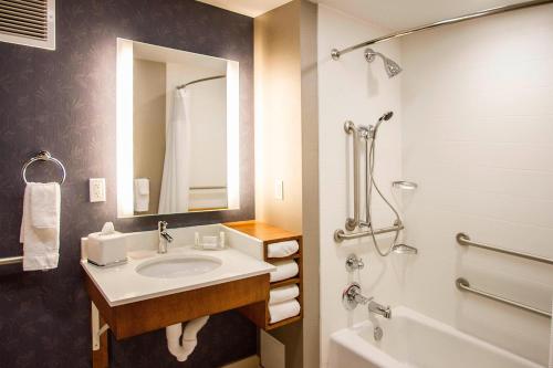 a bathroom with a sink and a mirror and a tub at SpringHill Suites by Marriott Deadwood in Deadwood
