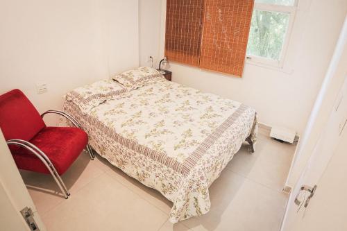 1 dormitorio con 1 cama y 1 silla roja en Leblon Aconchegante, en Río de Janeiro