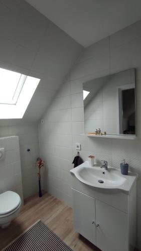 a white bathroom with a sink and a toilet at Vadgalamb Apartmanház in Lipót